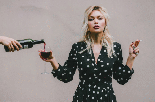 Une femme tenant une cigarette dans une main, et un verre d'alcool dans l'autre
